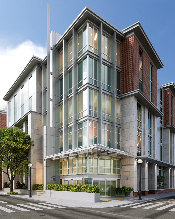 A modern building with glass windows and brick siding is on a corner with crosswalks and trees, under a clear blue sky.