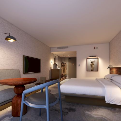 A modern hotel room with a bed, sofa, wall-mounted TV, and stylish lighting. Minimalist decor with neutral colors and a cozy ambiance.