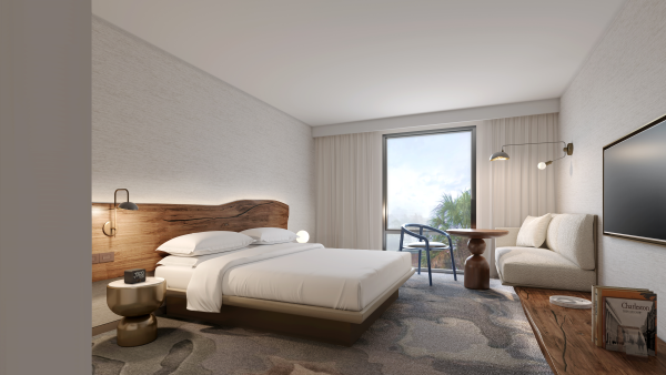 A modern hotel room features a bed, a sofa, a TV, a small table, and a window with a view, creating a cozy and inviting atmosphere.