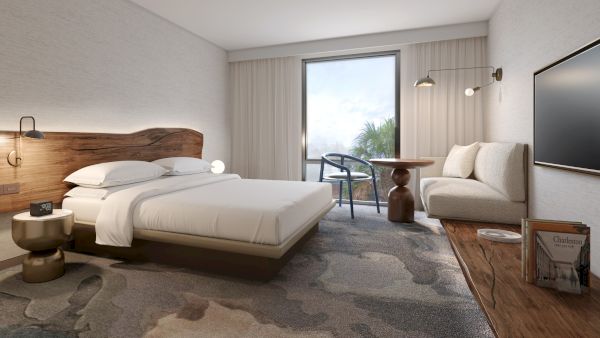 A modern hotel room with a bed, sofa, wooden furnishings, large window, and wall-mounted TV, offering a cozy and inviting atmosphere.