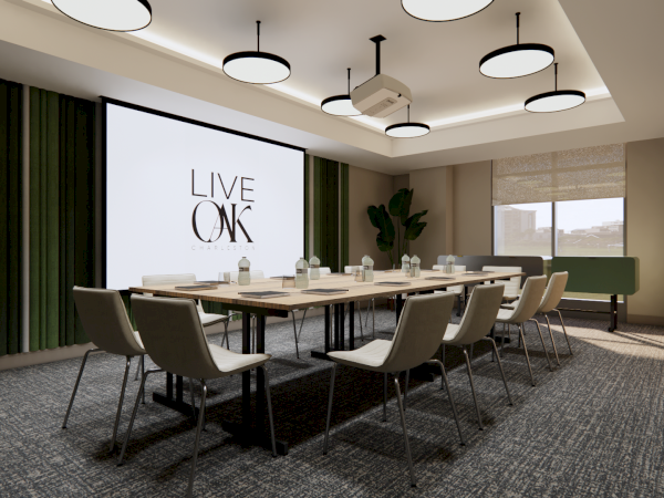 A modern conference room with a large screen displaying "LIVE OAK," surrounded by chairs, tables, and stylish lighting fixtures.