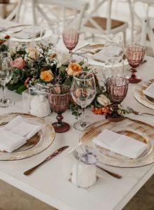 A beautifully set dining table with elegant tableware, floral centerpieces, and neatly folded napkins on plates, ready for guests.