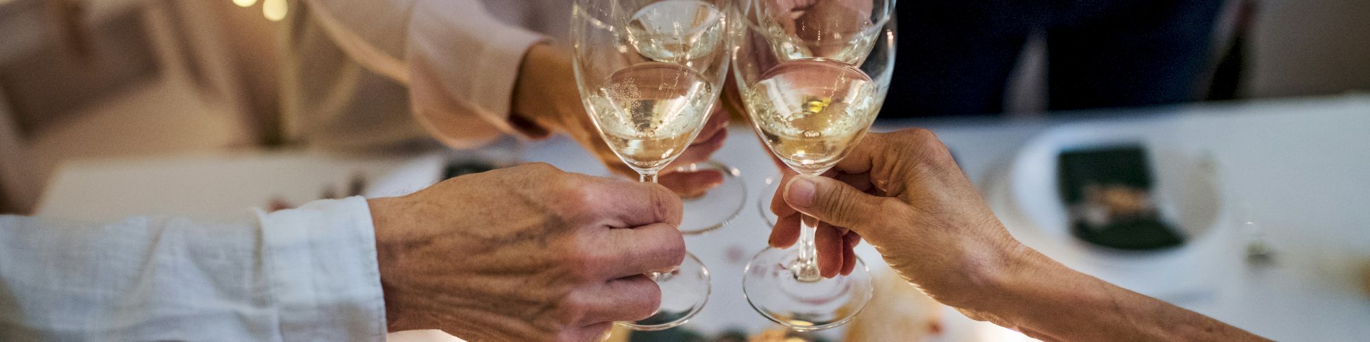 People are clinking glasses in a celebratory toast over a decorated festive table.