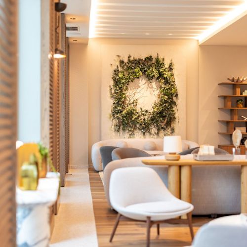 A cozy, sunlit reading nook with a wooden chair, small table, and stacked firewood beside a window, radiating warmth.