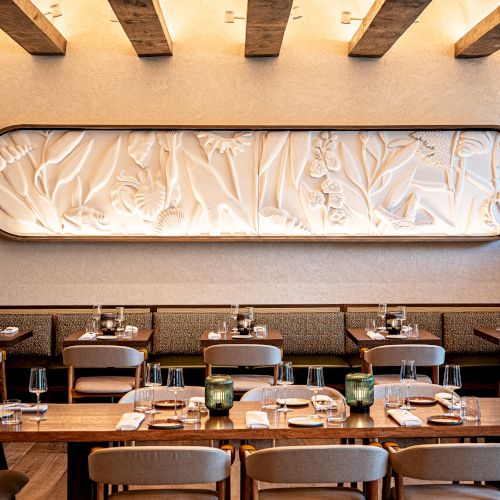 A bright, modern classroom with desks in rows, a whiteboard, and a large window letting in natural light, topped with a curved ceiling feature.