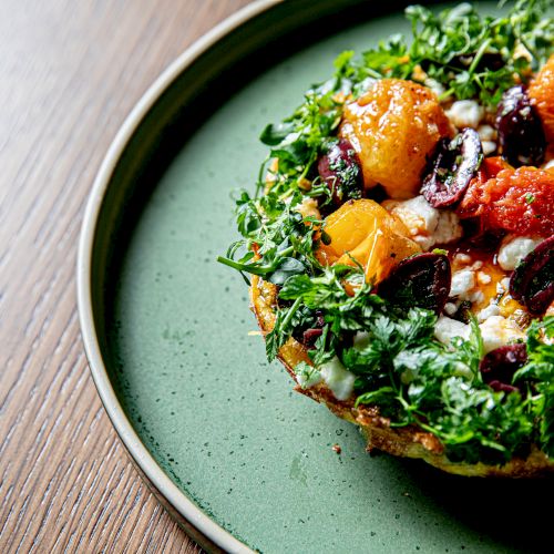 Delicious plated dish with greens and colorful toppings on a green plate, garnished and ready to serve.