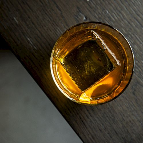 A close-up of a gold ring with a large orange gemstone, set on a dark surface.