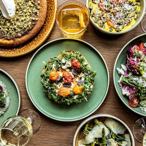 Assorted bowls of colorful, bite-sized foods&mdash;salads, grains, veggies, and toppings&mdash;presented in a vibrant, communal spread.