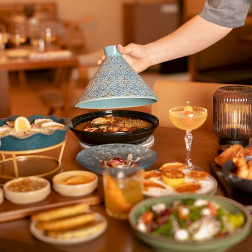 A cozy table with tea, cupcakes, and a teapot; assorted pastries and treats arranged on a wooden table.