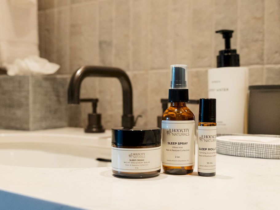 A bathroom counter with skincare products: jars and bottles arranged near a sink and faucet.