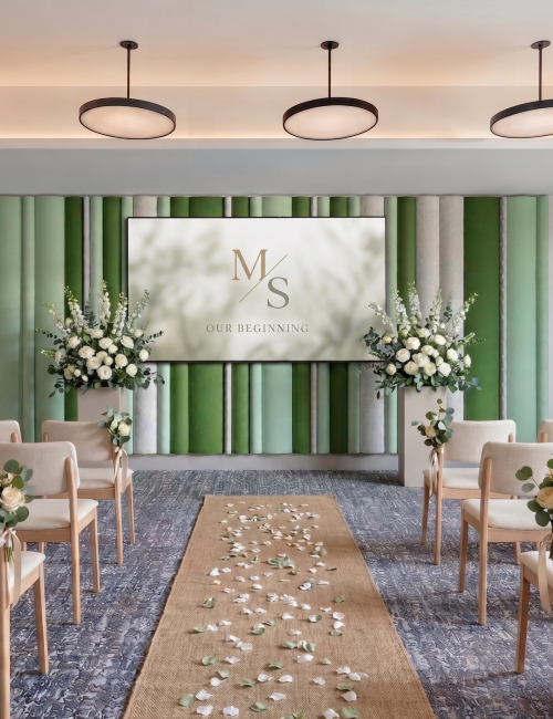 A wedding ceremony setup: rows of white chairs facing a floral arch, green striped backdrop, &ldquo;OUR BEGINNING&rdquo; sign, hanging lights, and rose petals on a runner.